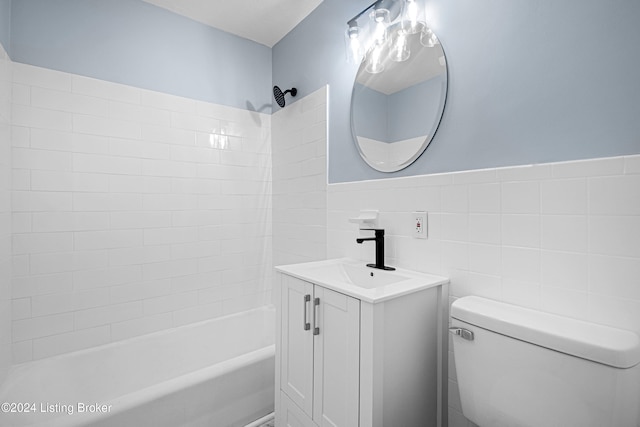 full bathroom with vanity, toilet, tile walls, and tiled shower / bath