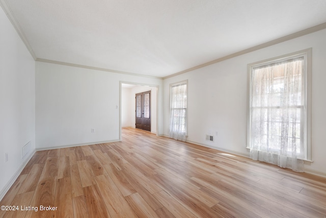 empty room with crown molding and light wood-type flooring