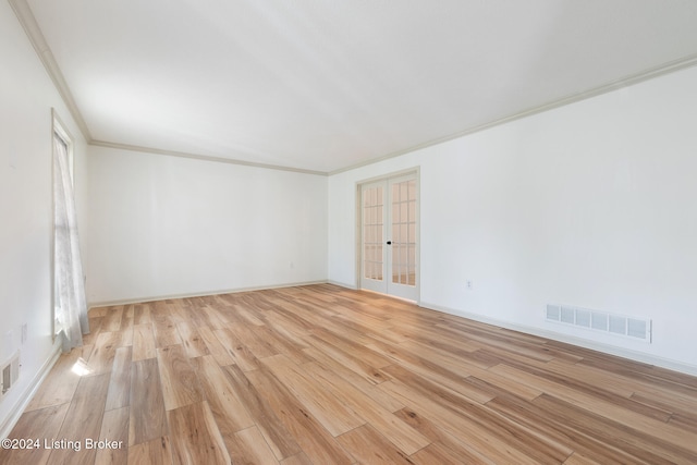 empty room featuring ornamental molding, french doors, and light hardwood / wood-style floors