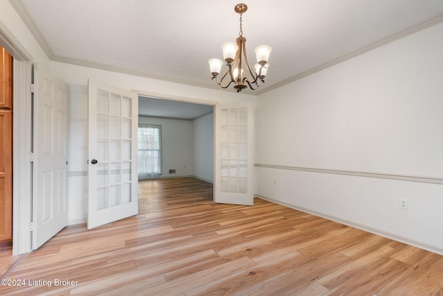 spare room featuring french doors, crown molding, a chandelier, and light wood-type flooring