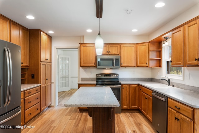 kitchen with a kitchen island, light wood-type flooring, sink, pendant lighting, and stainless steel appliances