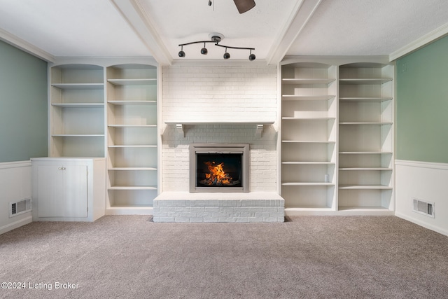 unfurnished living room with beam ceiling, carpet, a fireplace, and built in shelves