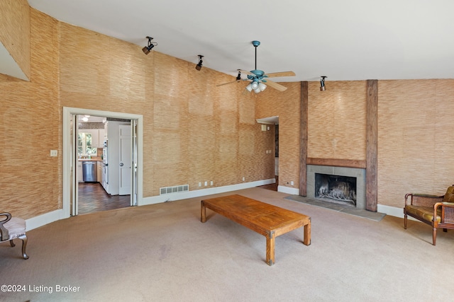 carpeted living room featuring ceiling fan, a tile fireplace, and a high ceiling