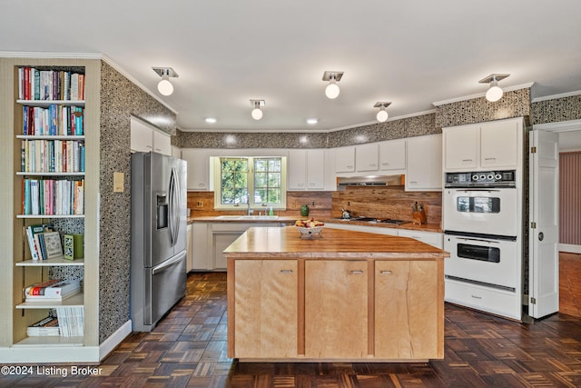 kitchen with gas stovetop, white cabinetry, stainless steel fridge, double oven, and a kitchen island