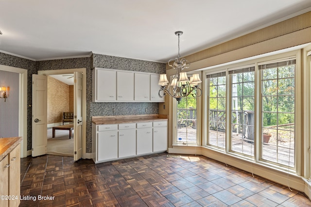 kitchen with dark parquet floors, white cabinetry, hanging light fixtures, ornamental molding, and a notable chandelier