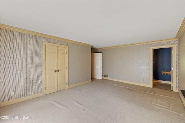 unfurnished bedroom with crown molding, light colored carpet, ensuite bath, and a closet