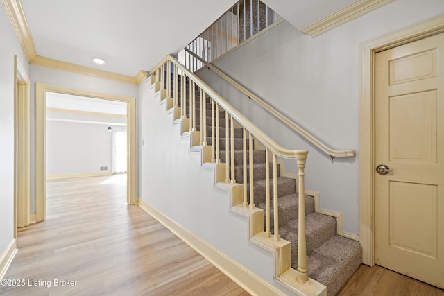 staircase with crown molding and hardwood / wood-style flooring