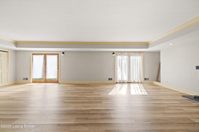 unfurnished room featuring crown molding, a raised ceiling, and light wood-type flooring