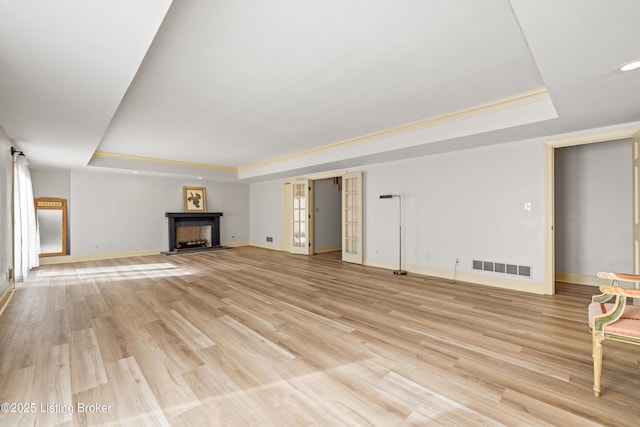 unfurnished living room featuring a tray ceiling and light wood-type flooring