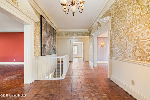 hallway featuring dark parquet flooring, ornamental molding, and an inviting chandelier