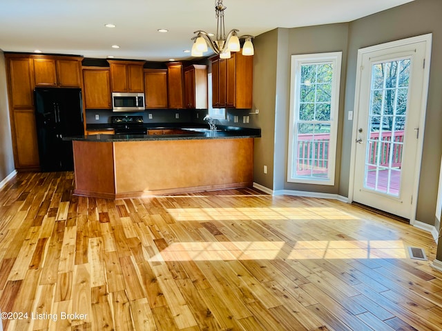 kitchen with black appliances, hanging light fixtures, and light wood-type flooring