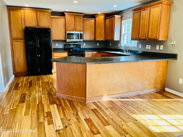 kitchen featuring light hardwood / wood-style floors, black appliances, sink, and kitchen peninsula