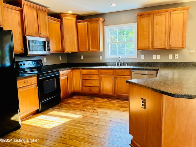 kitchen featuring sink, black appliances, and light wood-type flooring