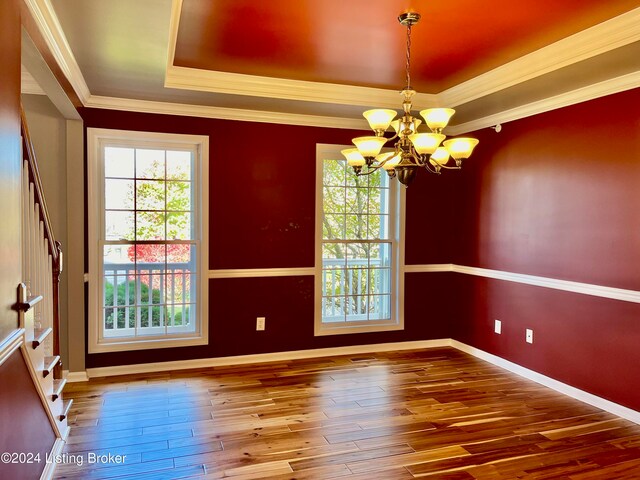 unfurnished room featuring crown molding, a tray ceiling, wood-type flooring, and an inviting chandelier