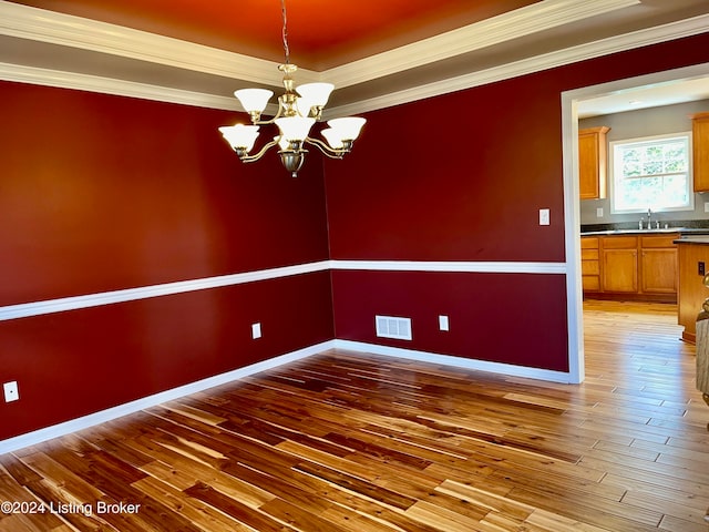 spare room featuring ornamental molding, sink, hardwood / wood-style flooring, and an inviting chandelier