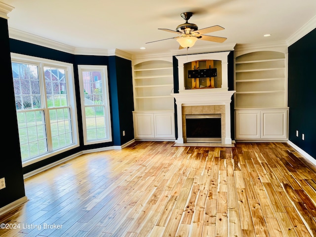 unfurnished living room with ornamental molding, a tile fireplace, light wood-type flooring, and ceiling fan