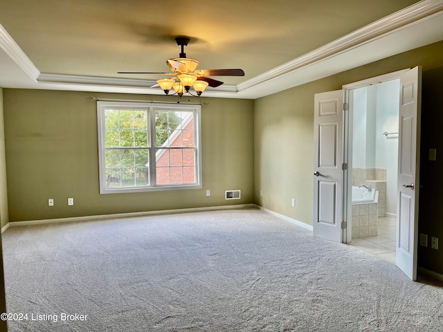 unfurnished bedroom with ceiling fan, light carpet, a raised ceiling, and ensuite bath