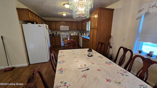 dining area featuring sink, a textured ceiling, dark hardwood / wood-style flooring, and an inviting chandelier