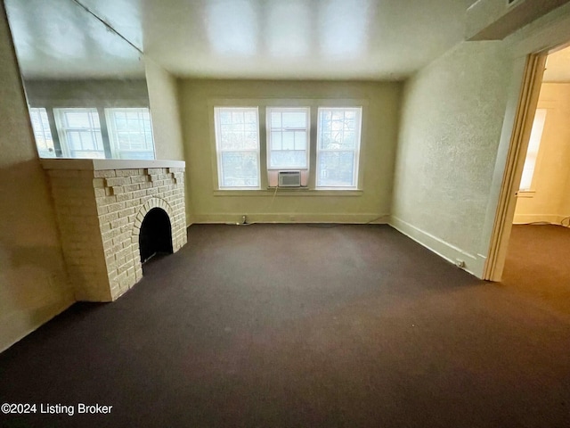 unfurnished living room featuring cooling unit, dark carpet, and a brick fireplace