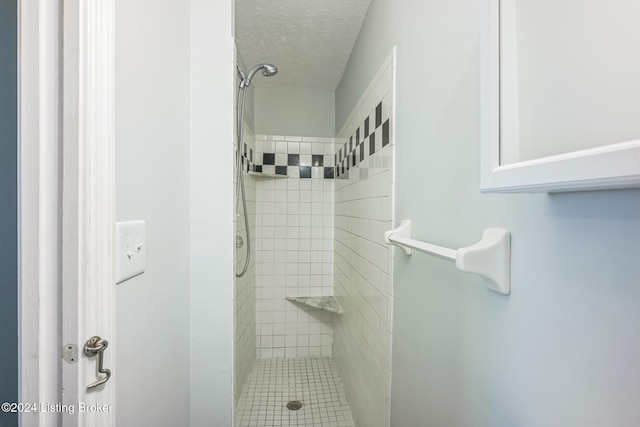 bathroom with tiled shower and a textured ceiling