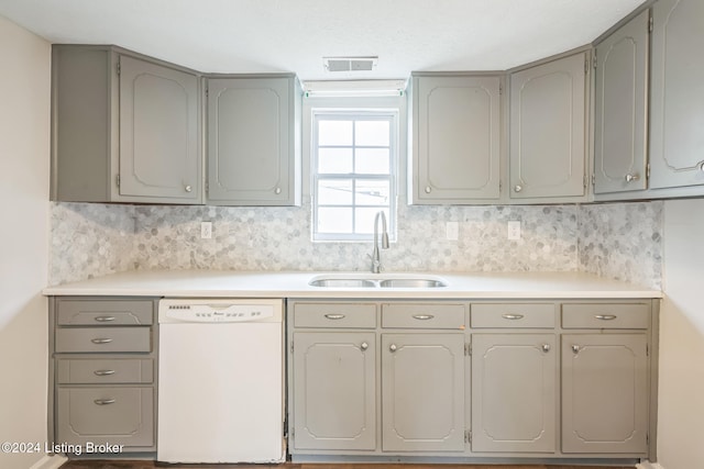 kitchen featuring dishwasher, sink, backsplash, and gray cabinetry