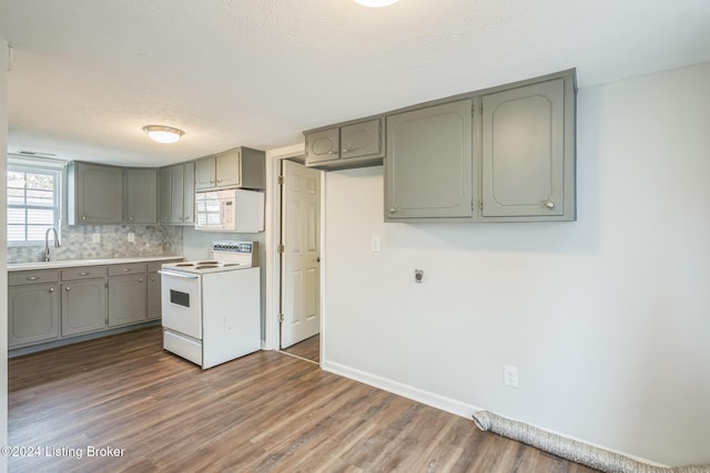 kitchen featuring dark wood-type flooring, gray cabinetry, white appliances, and sink