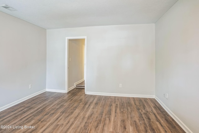 unfurnished room featuring dark wood-type flooring and a textured ceiling