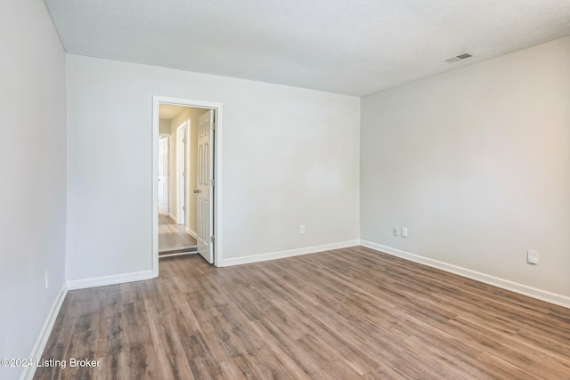 unfurnished room with a textured ceiling and hardwood / wood-style flooring