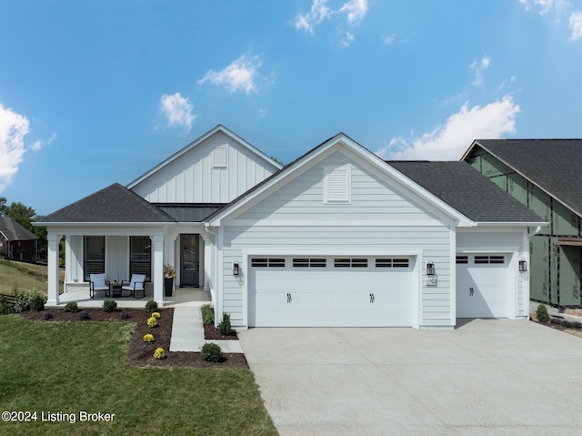 view of front of house featuring a front yard, covered porch, and a garage