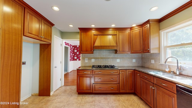 kitchen featuring dishwashing machine, light stone counters, custom exhaust hood, a sink, and stainless steel gas stovetop