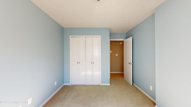 unfurnished bedroom featuring a closet, light colored carpet, and baseboards