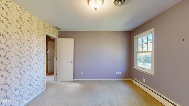 empty room featuring a baseboard heating unit, light colored carpet, baseboards, and a textured ceiling