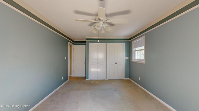 unfurnished bedroom with a ceiling fan, carpet, baseboards, a closet, and crown molding