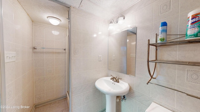 full bathroom with tile walls, a shower stall, and a textured ceiling