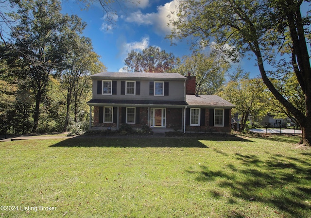 view of front of house featuring brick siding, a chimney, and a front yard