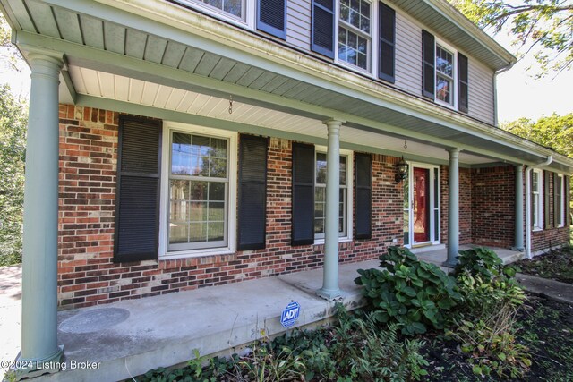 entrance to property with a porch and brick siding