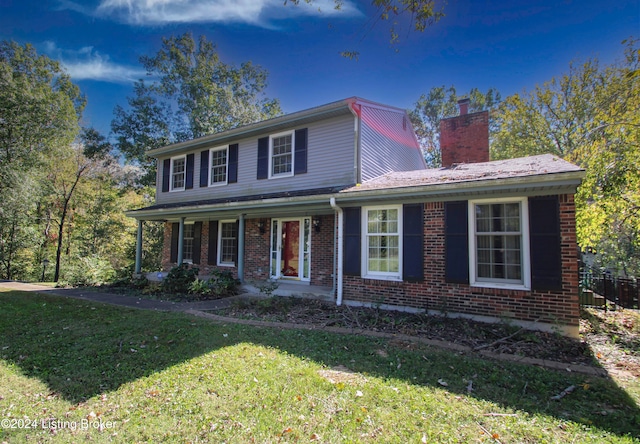 view of front of property with brick siding, a chimney, and a front lawn