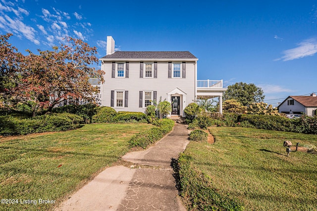 colonial-style house with a balcony and a front lawn