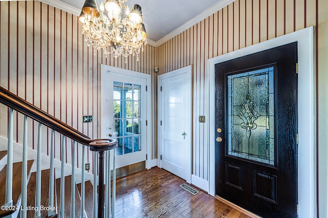 entrance foyer featuring ornamental molding, hardwood / wood-style floors, and an inviting chandelier