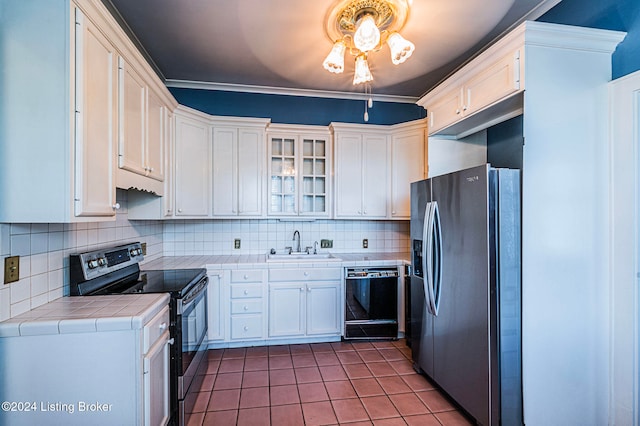 kitchen featuring tile patterned floors, tile countertops, backsplash, white cabinets, and appliances with stainless steel finishes