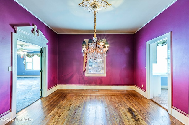 unfurnished dining area with ornamental molding, a chandelier, and wood-type flooring