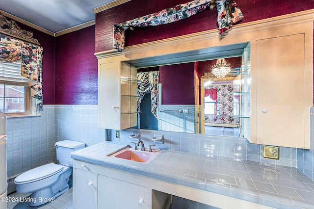 bathroom featuring toilet, tile patterned flooring, vanity, ornamental molding, and tile walls