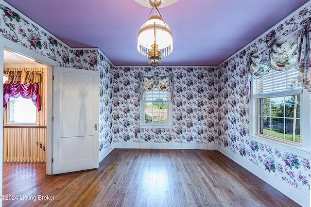 empty room with hardwood / wood-style floors, a chandelier, and plenty of natural light