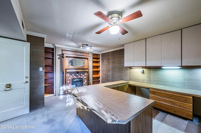 kitchen featuring a kitchen island, a fireplace, white cabinetry, ceiling fan, and ornamental molding