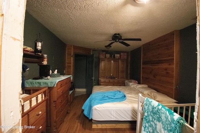 bedroom with lofted ceiling, wood-type flooring, ceiling fan, a textured ceiling, and wood walls