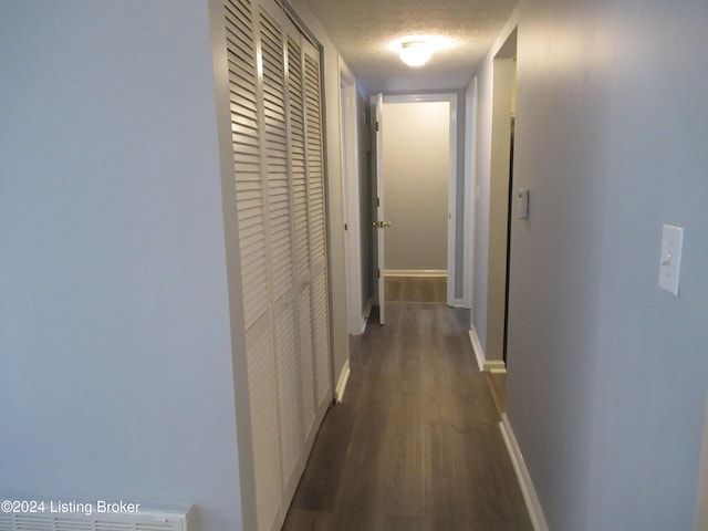 hall with a textured ceiling and dark hardwood / wood-style flooring