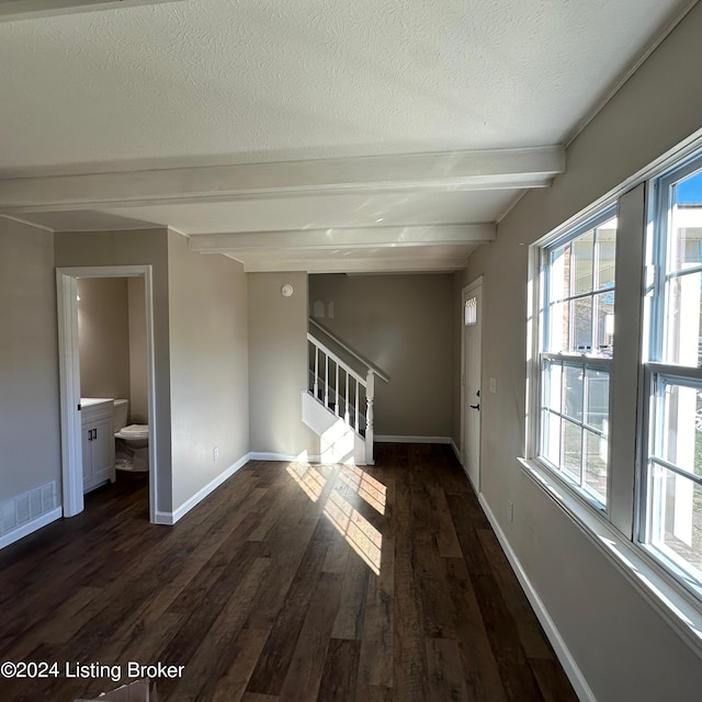 interior space with dark hardwood / wood-style flooring, beamed ceiling, and a textured ceiling