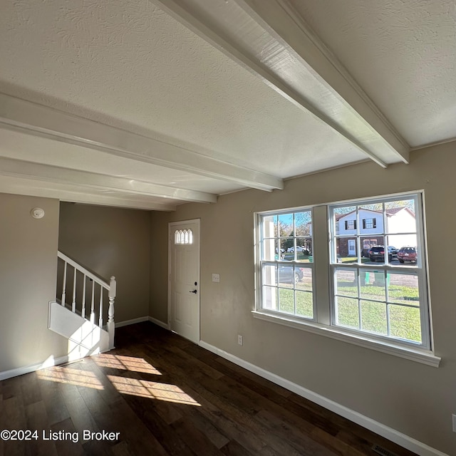 entrance foyer with beamed ceiling, dark hardwood / wood-style floors, a healthy amount of sunlight, and a textured ceiling