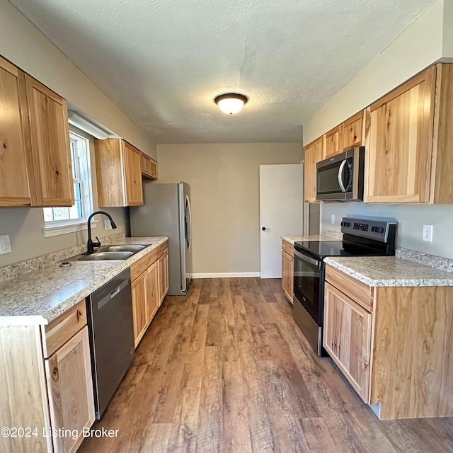 kitchen with a textured ceiling, sink, dark hardwood / wood-style floors, light stone countertops, and appliances with stainless steel finishes