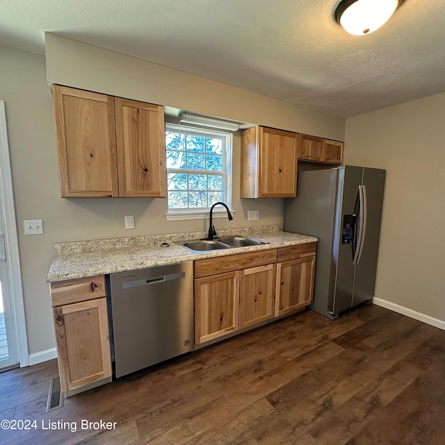 kitchen with stainless steel appliances, sink, light stone countertops, a textured ceiling, and dark hardwood / wood-style flooring